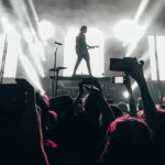 Silhouette of a musician performing live on stage with energetic audience. Captures the essence of nightlife entertainment.